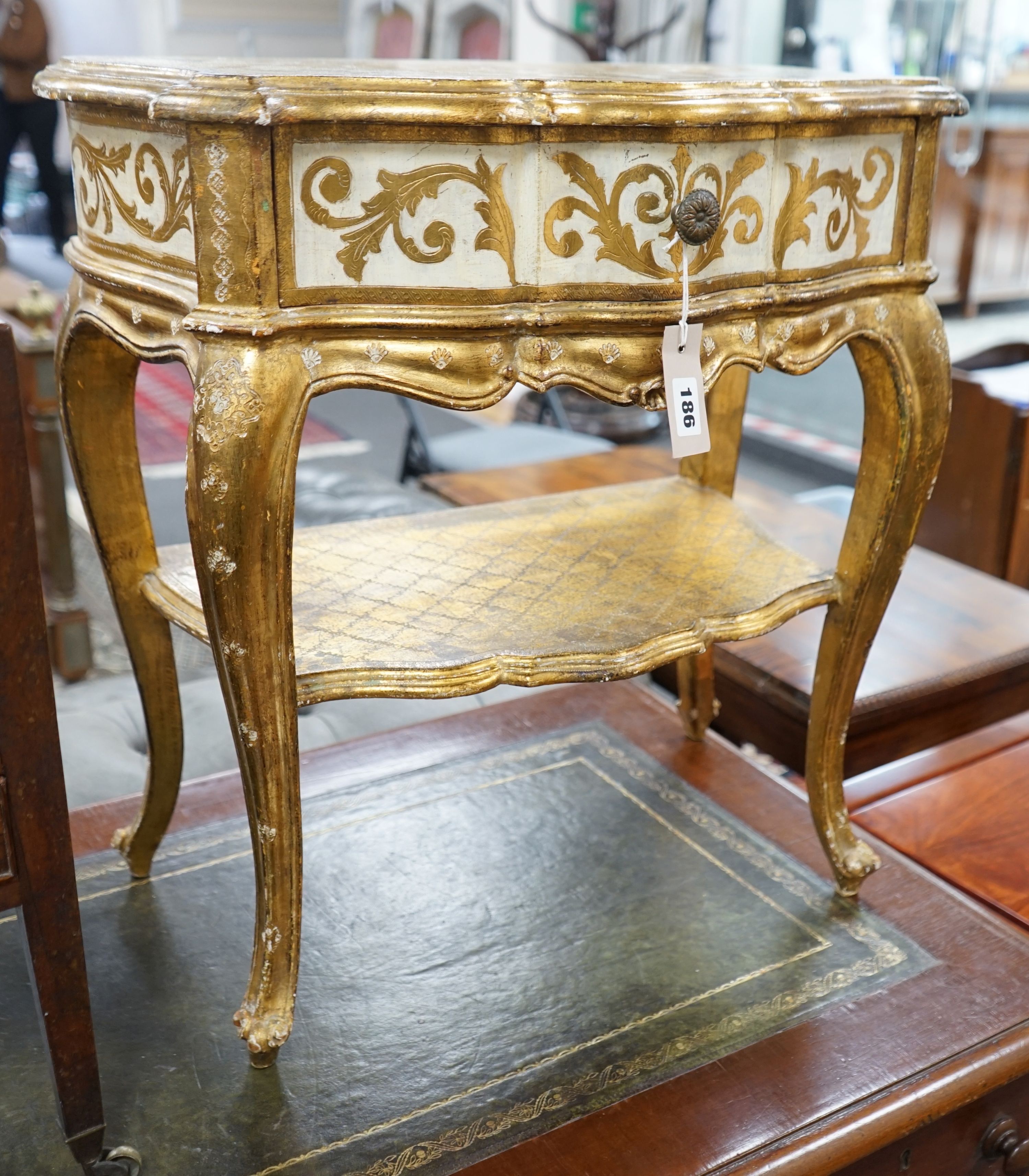 A Florentine gilt and cream painted serpentine two tier side table, width 50cm, depth 34cm, height 58cm